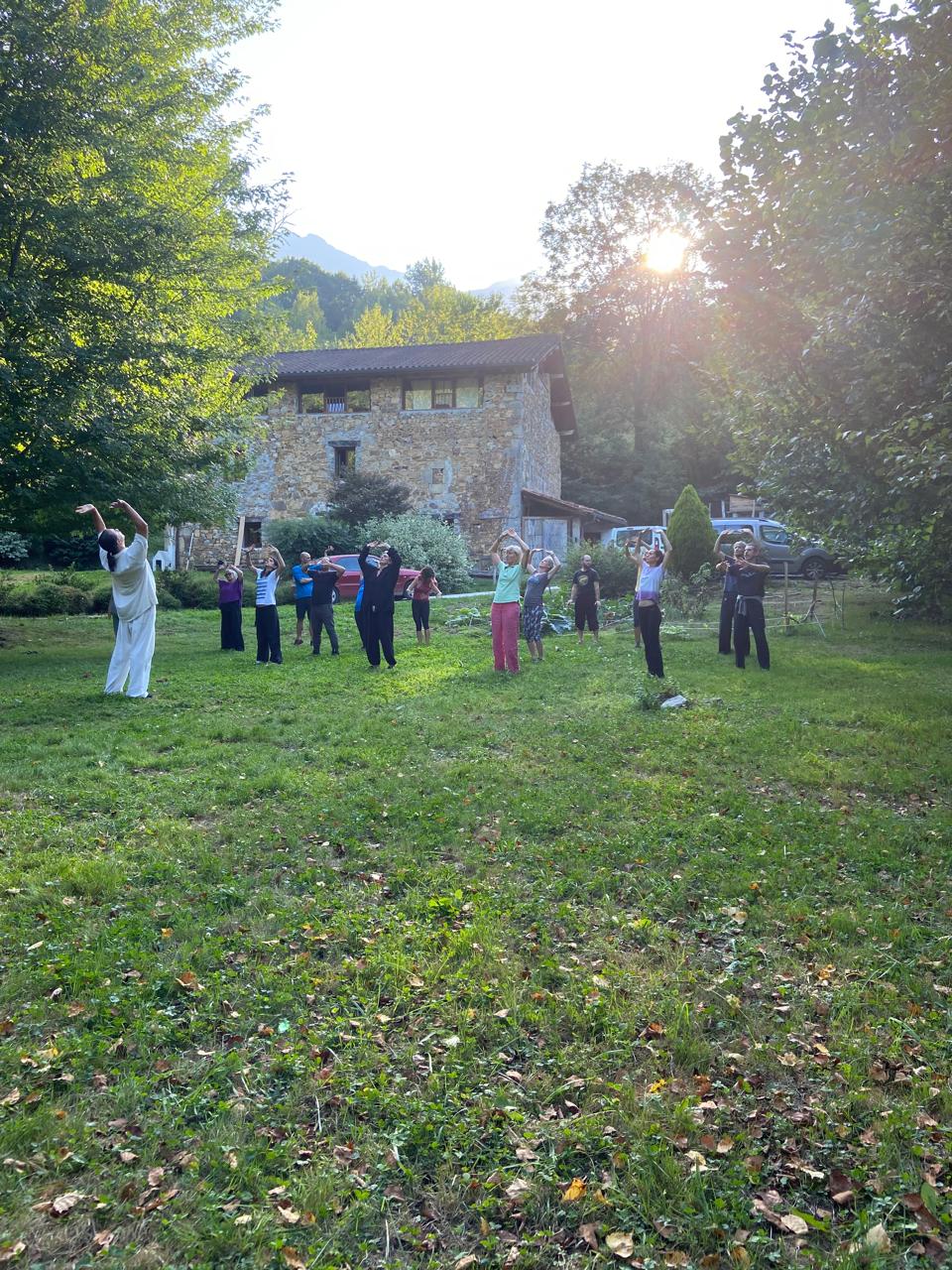 Groupe en pratique au crépuscule devant la maison de pierre
